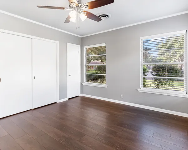 a view of an empty room with a window and wooden floor