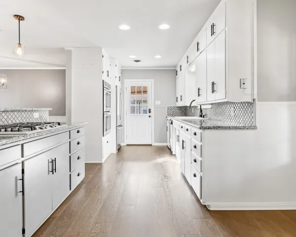 a large kitchen with granite countertop a lot of counter space and wooden floor
