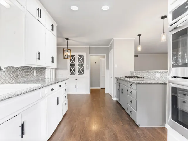 a large kitchen with granite countertop a lot of counter space and wooden floor