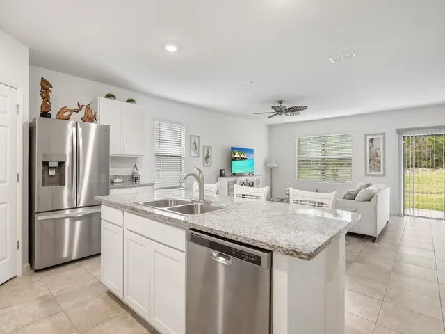 a kitchen with stainless steel appliances granite countertop a sink refrigerator and cabinets
