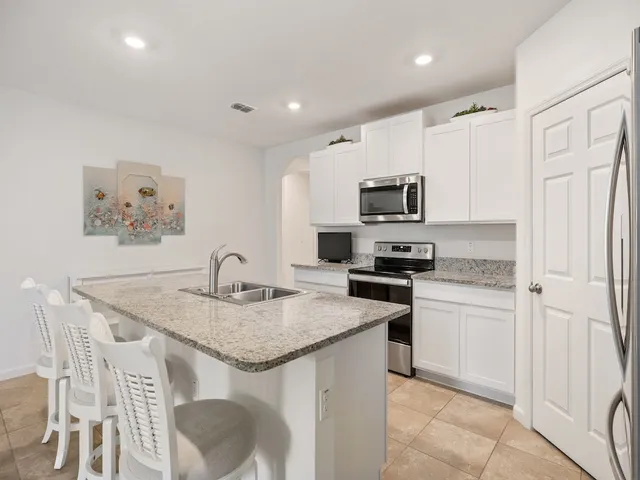 a kitchen with kitchen island granite countertop stainless steel appliances stove microwave and sink