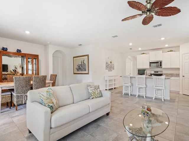 a living room with furniture kitchen view and a wooden floor