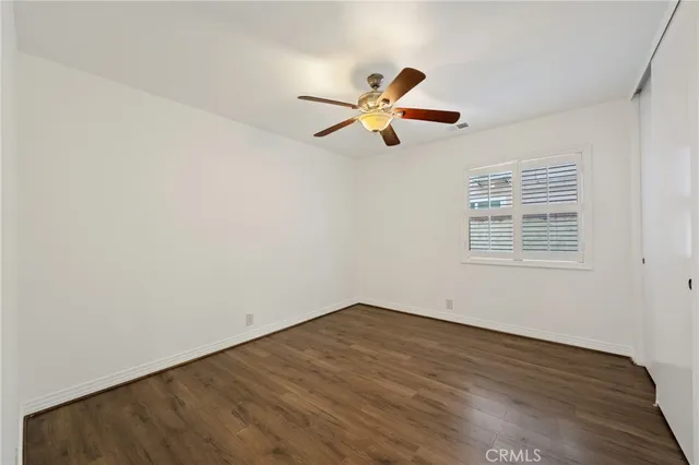 an empty room with wooden floor ceiling fan and windows