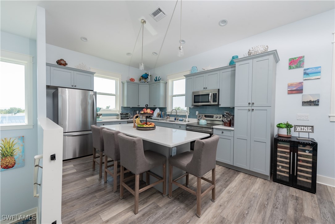4500 Butterfly Shell Drive Captiva, FL 33924 - Photo 10 of 42 a kitchen with stainless steel appliances a refrigerator a stove a sink dishwasher and a dining table with wooden floor