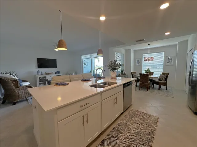 a large white kitchen with a sink a stove and a chandelier