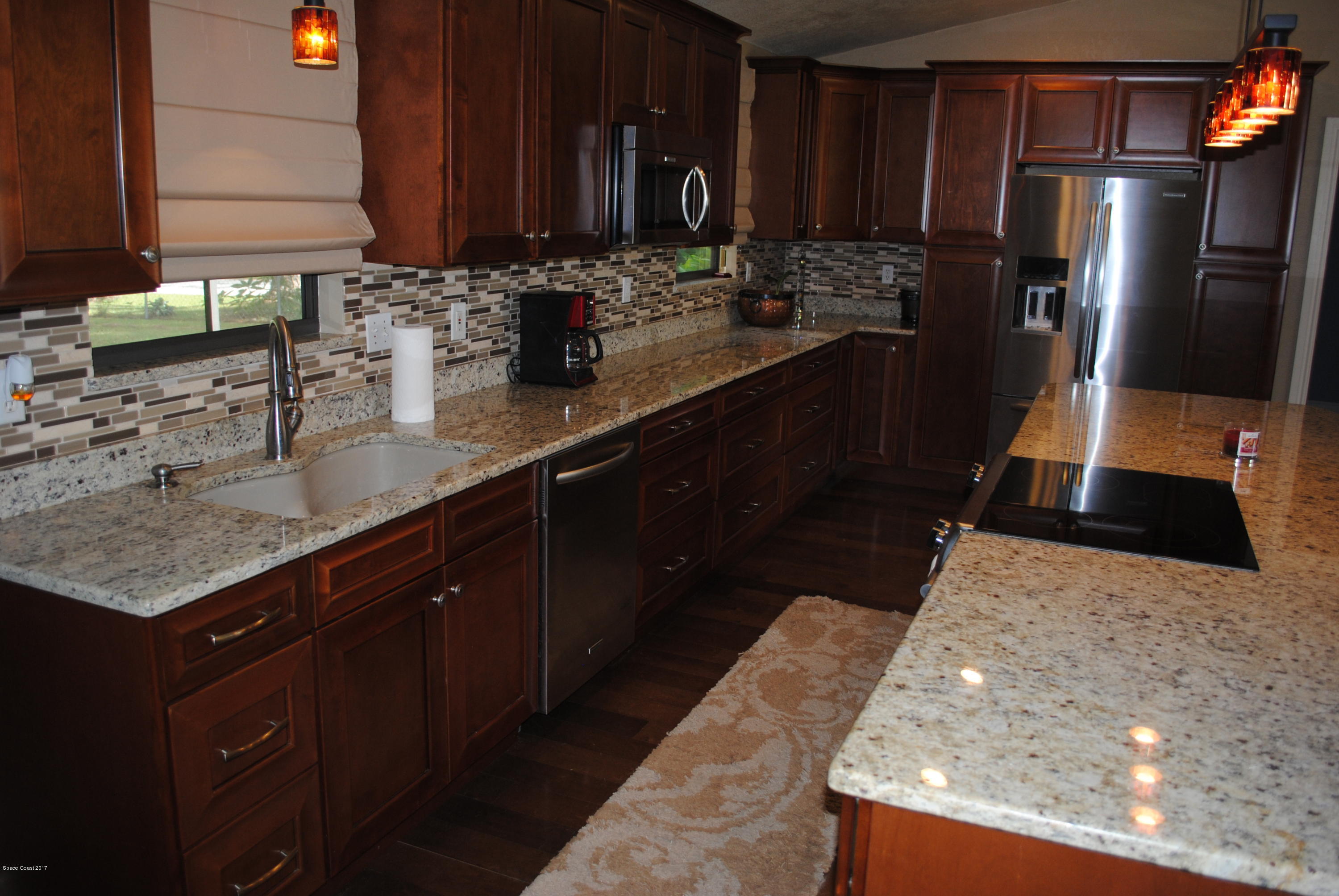 399 Warner Road Southwest Palm Bay, FL 32908 - Photo 3 of 40 a kitchen with stainless steel appliances kitchen island granite countertop a sink stove and refrigerator