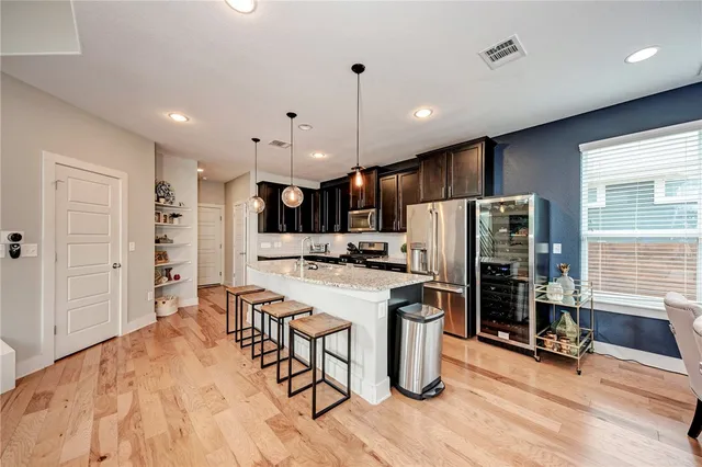a kitchen with a refrigerator a oven and a sink with wooden floor
