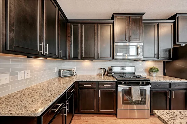 a kitchen with kitchen island granite countertop a sink stove and refrigerator