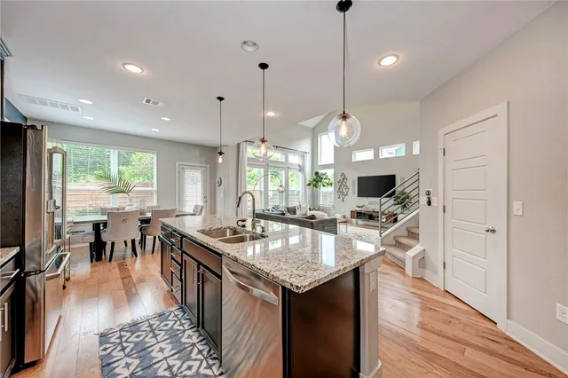 a kitchen with granite countertop a stove a sink a dining table and chairs with wooden floor