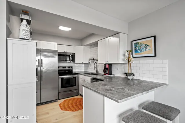 a kitchen with stainless steel appliances granite countertop a refrigerator a stove and a sink with wooden floor