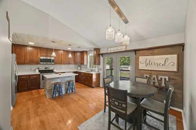 a kitchen with a dining table chairs stainless steel appliances and cabinets