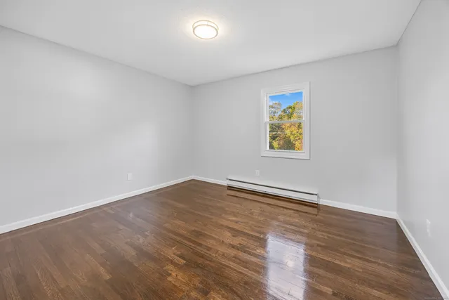 an empty room with wooden floor and window