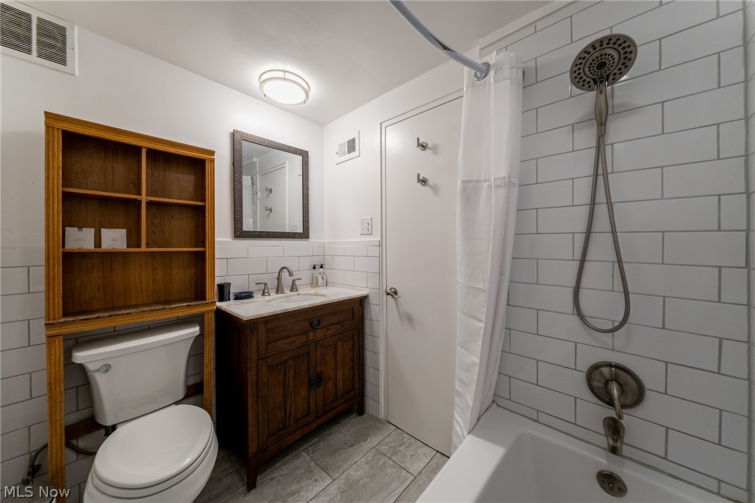 13800 Fairhill Road, Unit 306 Cleveland, OH 44120 - Photo 36 of 48 Full bath with vanity, shower / tub combo, light tile patterned floors, tile walls, and a wainscoted wall