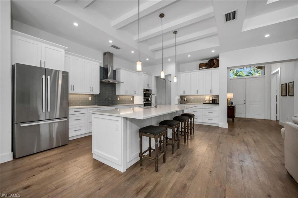 7437 Acorn Way Naples, FL 34119 - Photo 3 of 19 a kitchen with stainless steel appliances granite countertop a refrigerator a stove top oven a sink dishwasher and a dining table with wooden floor
