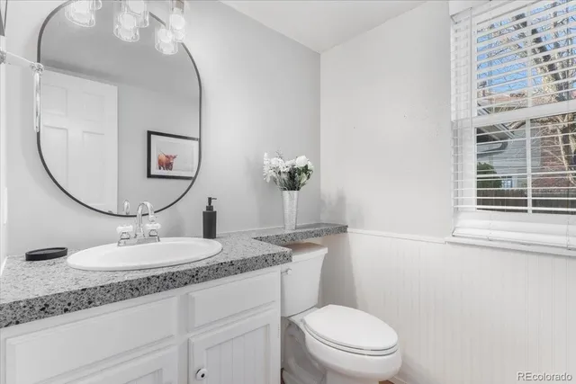 a bathroom with a granite countertop toilet a sink and a mirror