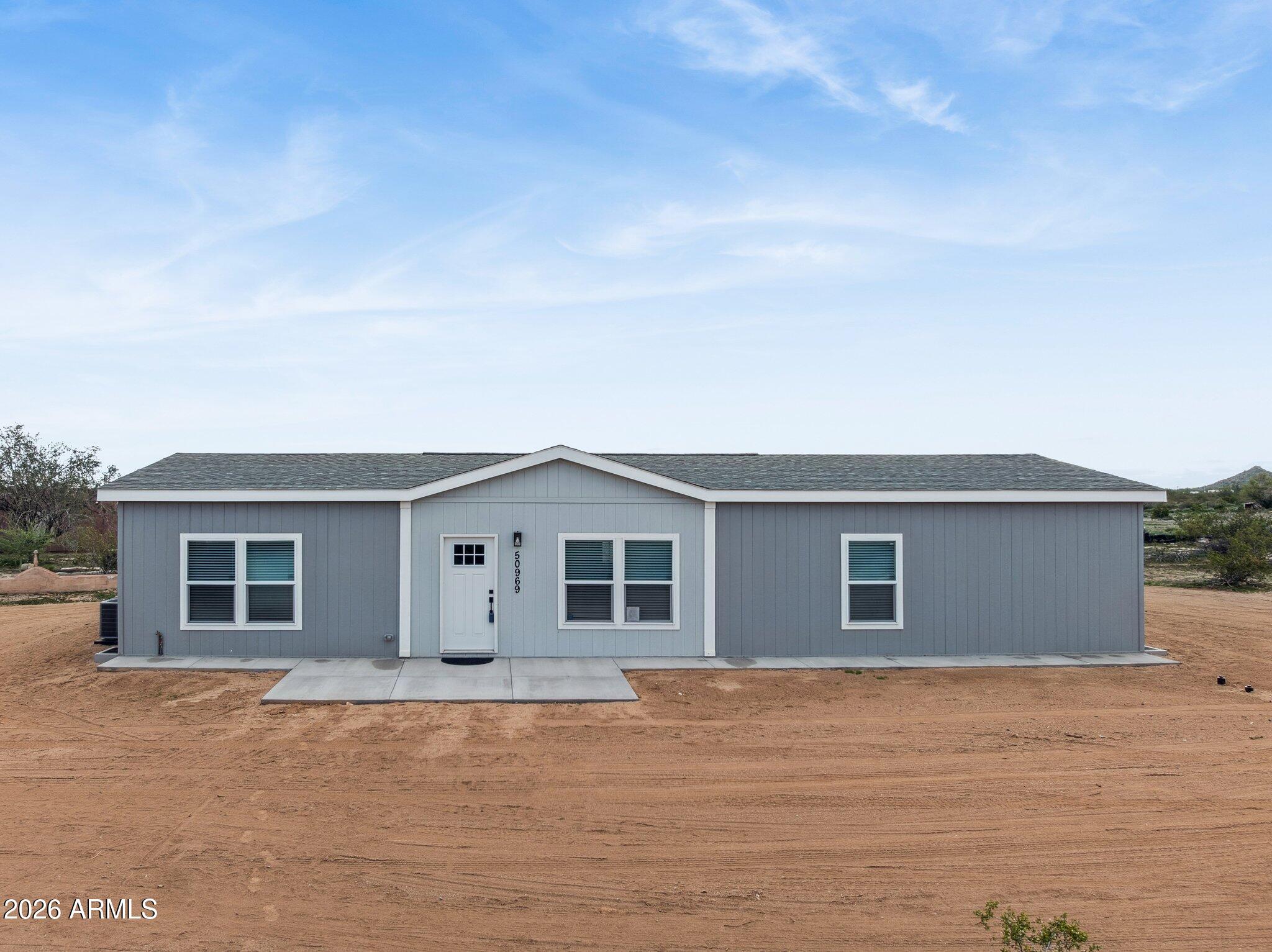a front view of house with yard and trees in the background