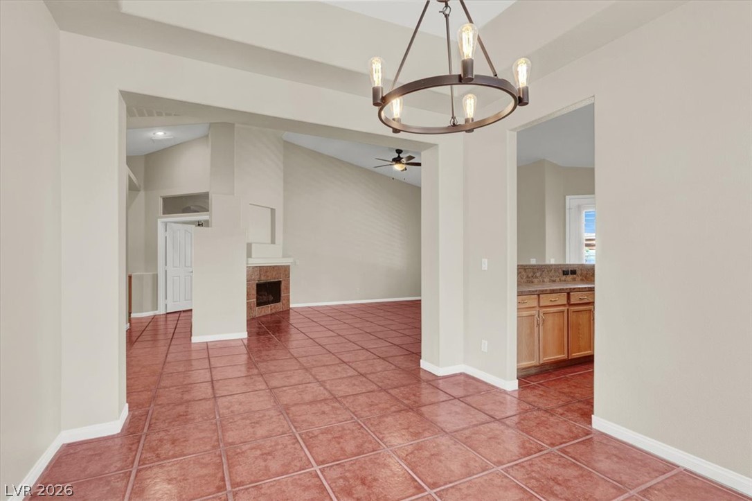 7308 Rustic Meadow Street Las Vegas, NV 89131 - Photo 6 of 27 A terracotta-tiled open concept space featuring a fireplace and a classic chandelier.