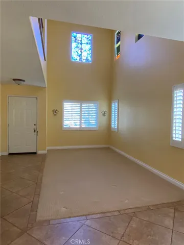 a view of a livingroom with an empty space a kitchen space and windows