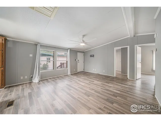 a view of an empty room with wooden floor and window