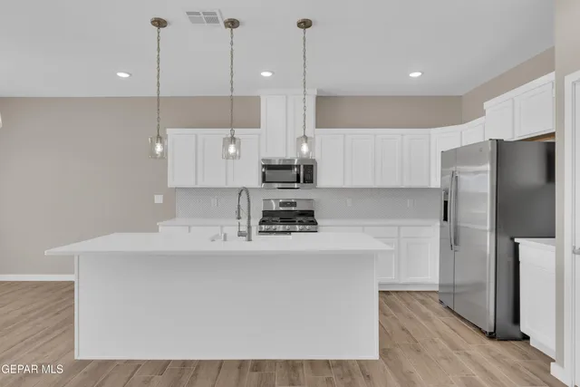 a kitchen with stainless steel appliances a sink a stove top oven a counter space and cabinets