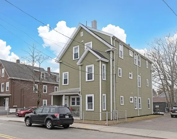 a front view of a house with a large tree and wooden fence