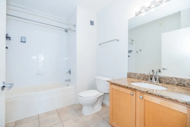 a bathroom with a granite countertop sink a toilet and shower