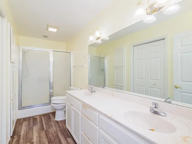 a bathroom with a double vanity sink a toilet and a shower