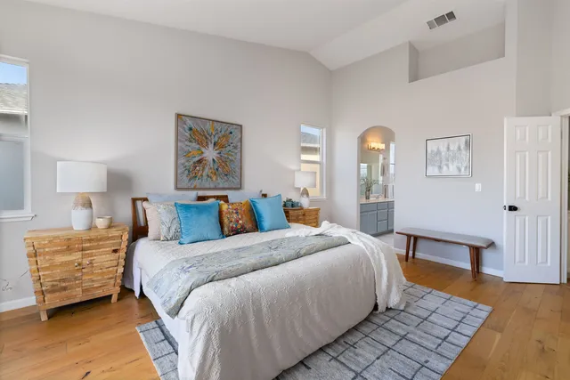 a bedroom with a bed a lamp on dresser and a wooden floor