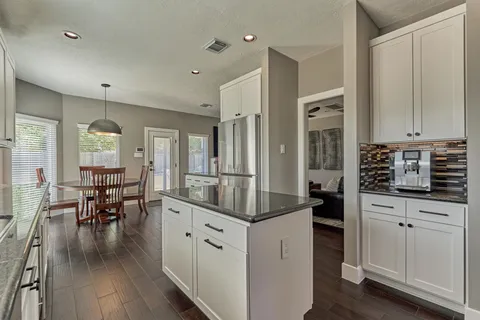 a kitchen with stainless steel appliances granite countertop a refrigerator a sink dishwasher a stove top oven a refrigerator and white cabinets with wooden floor