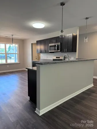 a kitchen with stainless steel appliances granite countertop a sink a stove top oven and wooden floor