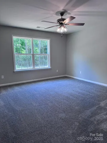 an empty room with a chandelier fan and windows