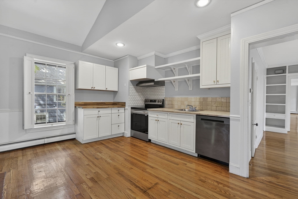12 Crown Street Worcester, MA 01609 - Photo 27 of 42 a kitchen with granite countertop a stove top oven a sink and white cabinets with wooden floor
