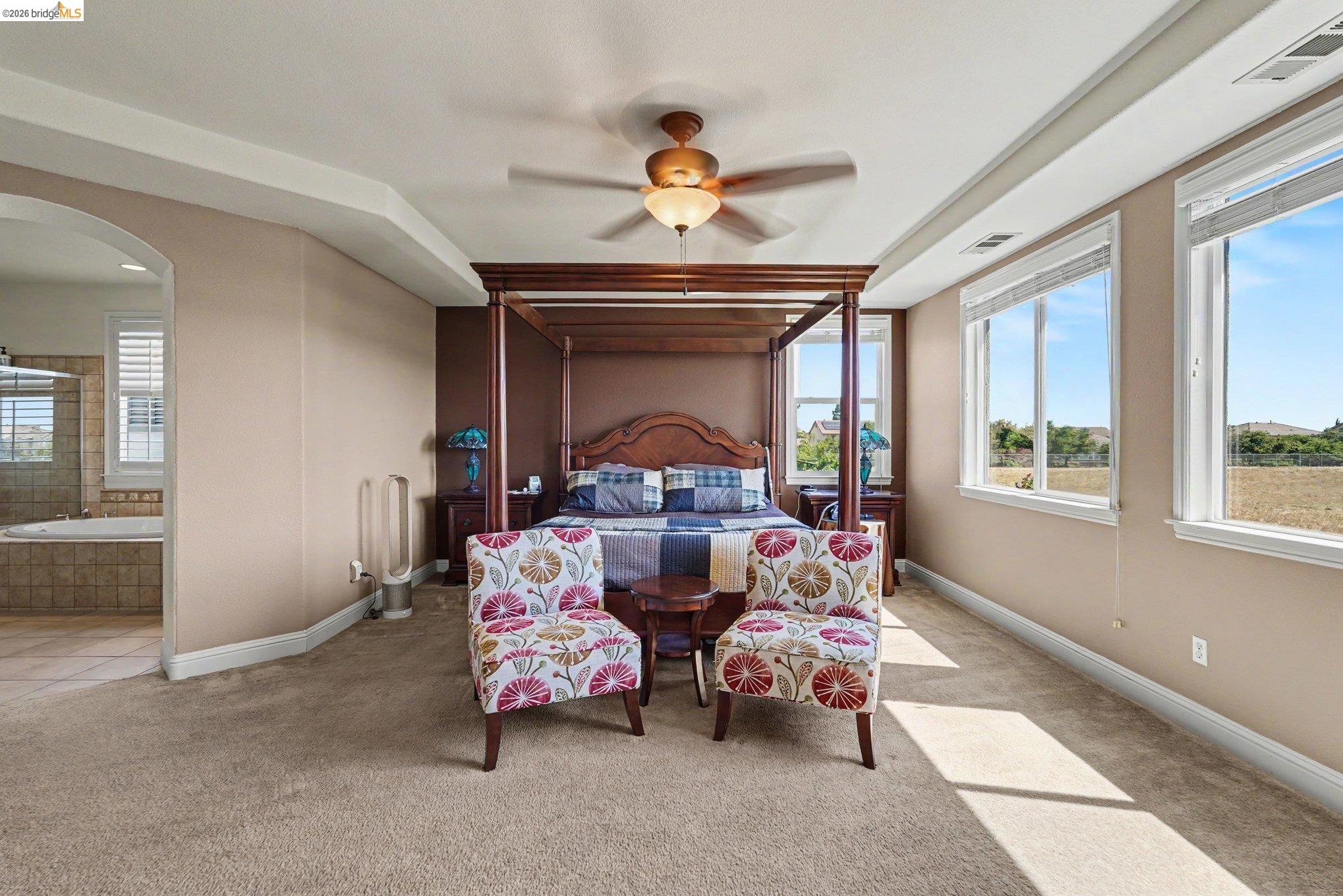 106 Little Ranch Circle Oakley, CA 94561 - Photo 22 of 34 Carpeted room featuring multiple windows, a ceiling fan with integrated lighting, and an archway leading to a tiled area with a built-in jetted tub
