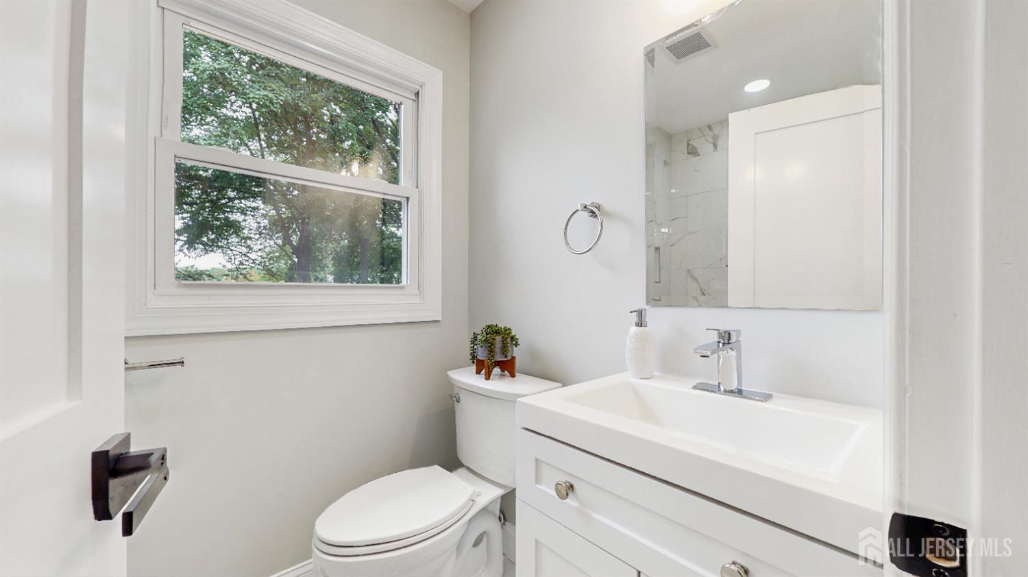 17 Tamarack Road Somerset, NJ 08873 - Photo 8 of 13 a bathroom with a sink a toilet a mirror and a window