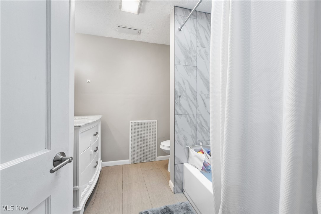 1620 Sunview Road Cleveland, OH 44124 - Photo 24 of 36 Full bathroom featuring vanity, a textured ceiling, toilet, and shower / tub combo with curtain