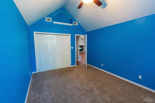 an empty room with chandelier fan and windows