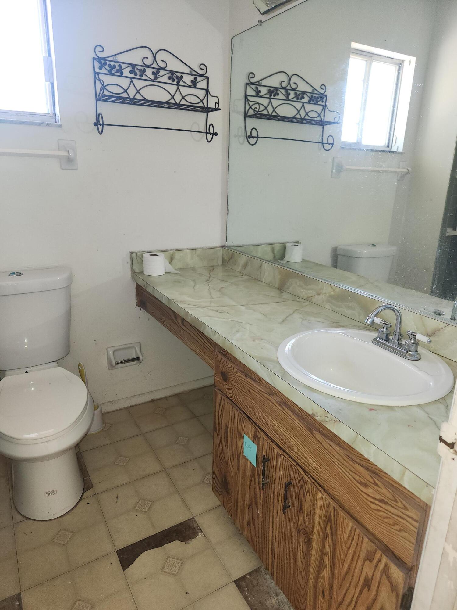951 Palm Street Cocoa, FL 32927 - Photo 17 of 34 a bathroom with a granite countertop sink a toilet and a mirror