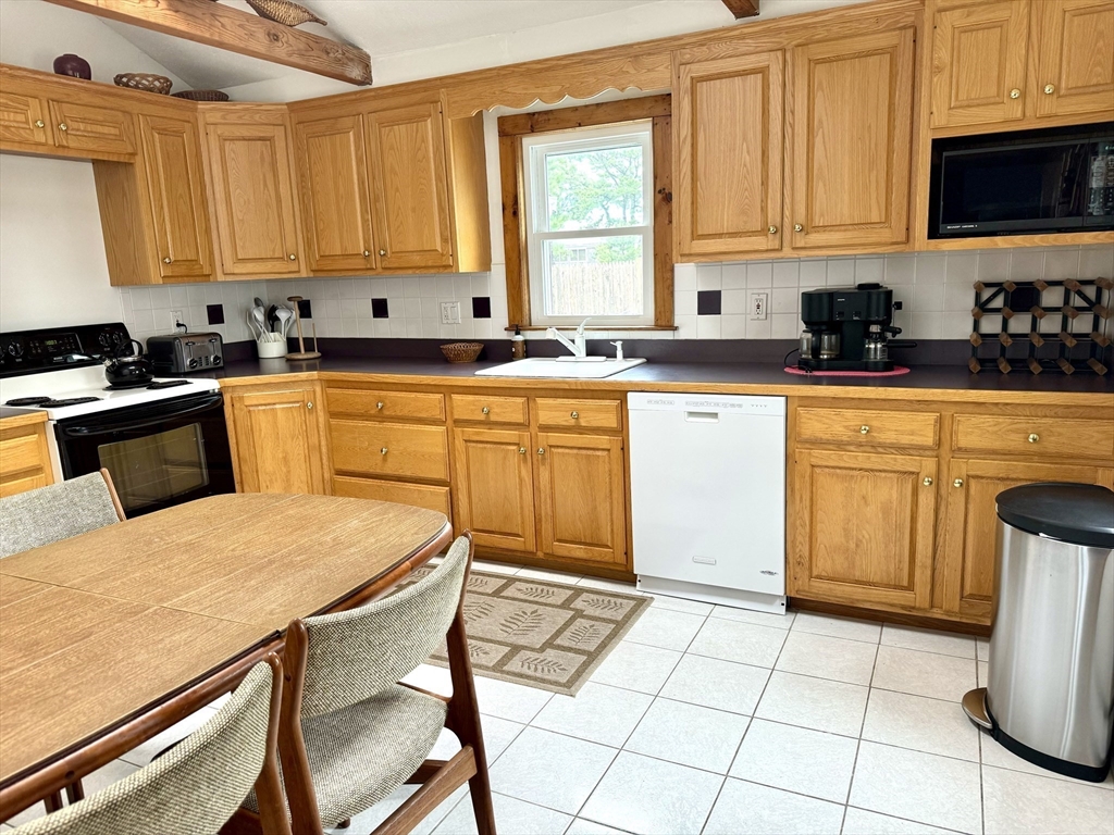 24 Shore Road West Dennis, MA 02670 - Photo 8 of 28 a kitchen with a stove a sink a microwave and cabinets