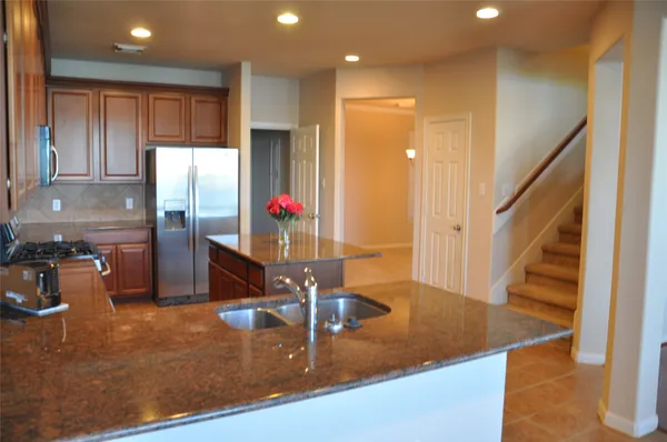 a kitchen with stainless steel appliances granite countertop a sink refrigerator and cabinets