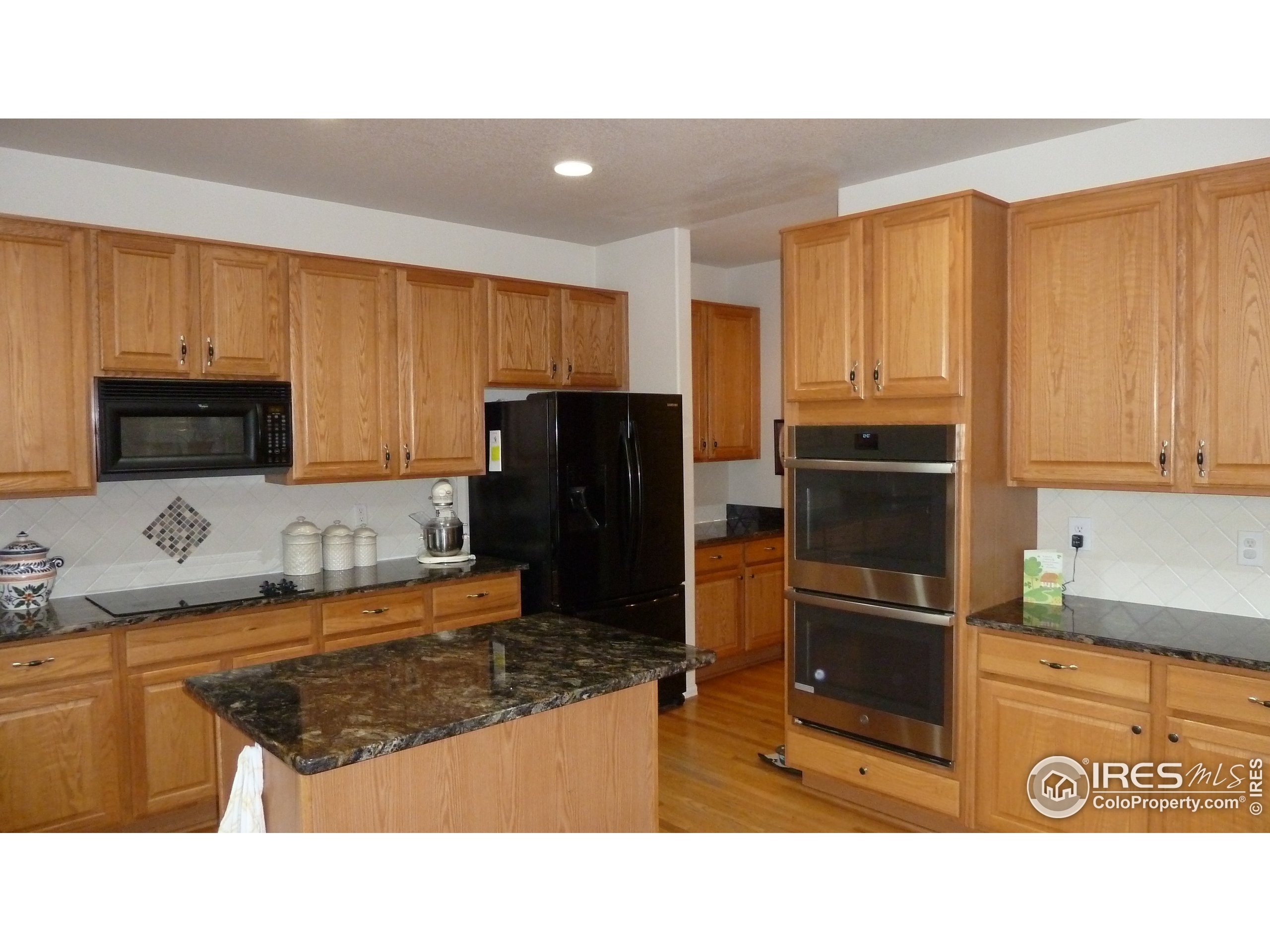 8121 Raspberry Drive Frederick, CO 80504 - Photo 4 of 38 a kitchen with stainless steel appliances kitchen island granite countertop a refrigerator stove and microwave