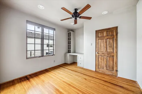 a view of empty room with wooden floor and fan