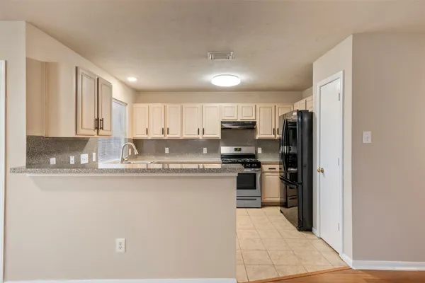 a kitchen with stainless steel appliances granite countertop a refrigerator stove top oven and sink