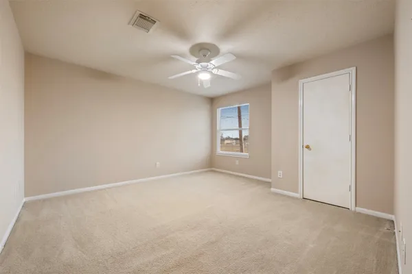 an empty room with a chandelier fan and windows
