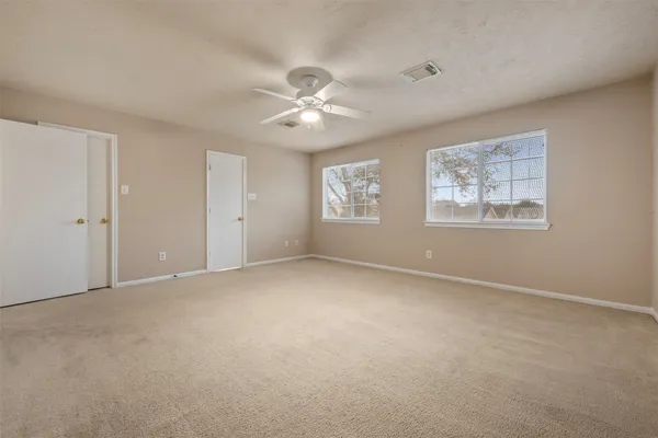 an empty room with windows and fan