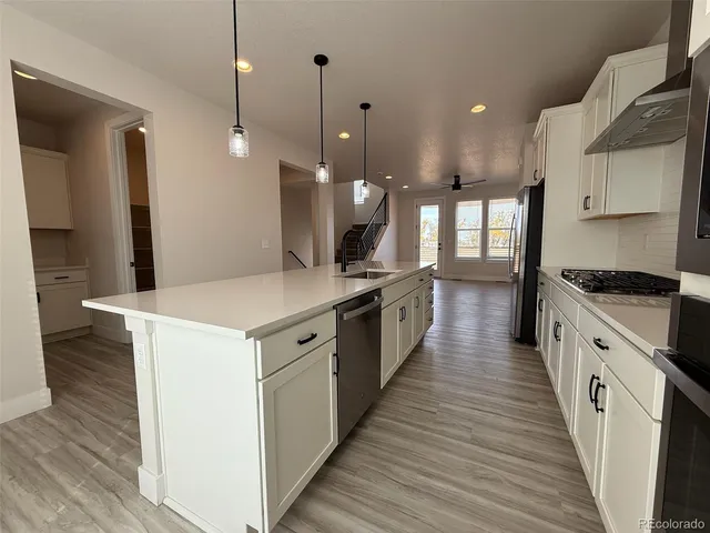 a large kitchen with granite countertop a large counter top a sink stainless steel appliances and cabinets