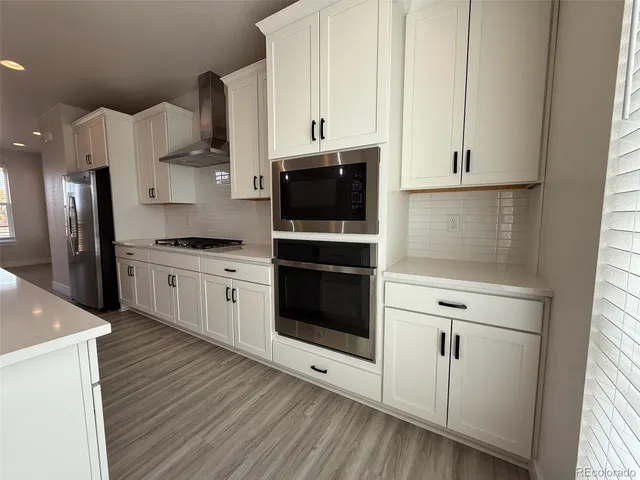 a kitchen with stainless steel appliances white cabinets and wooden floor