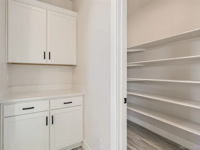 a view of closet with white cabinets