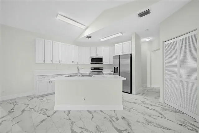 a view of kitchen with stainless steel appliances granite countertop a refrigerator a sink dishwasher and a stove with wooden floor