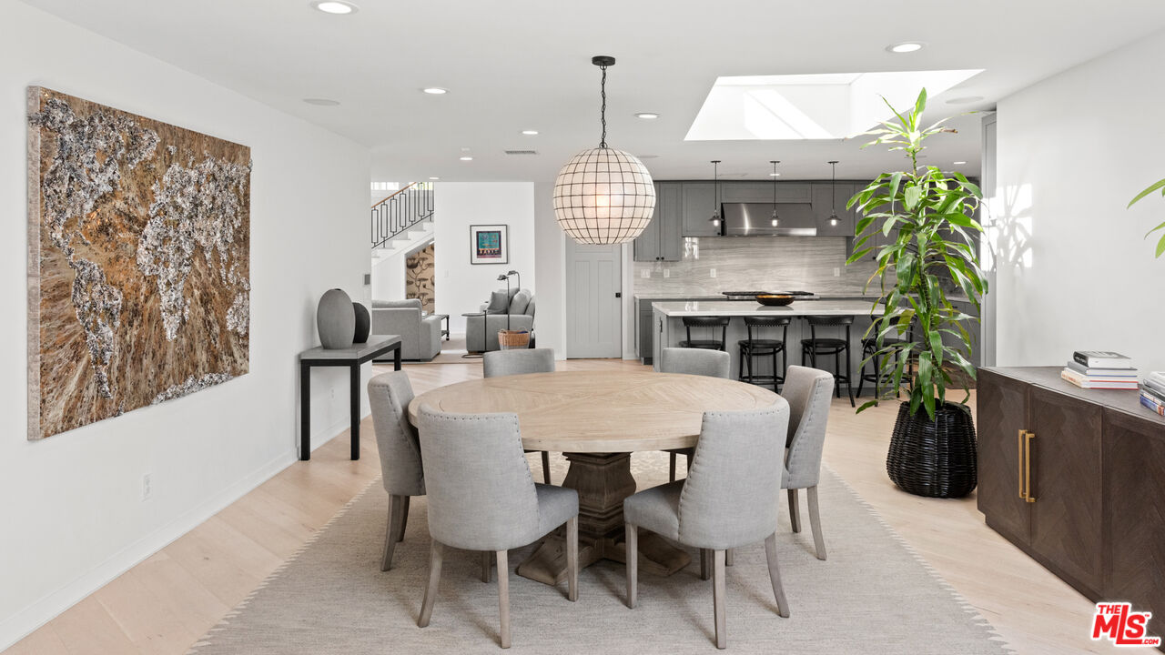 1944 North Beverly Drive Beverly Hills, CA 90210 - Photo 7 of 29 a dining room with a table chairs and a kitchen view