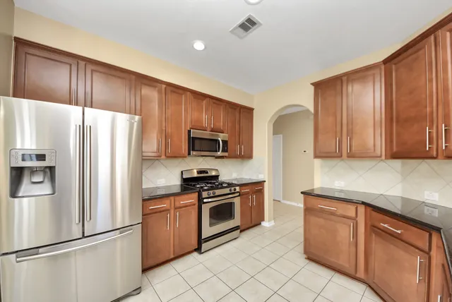 a kitchen with stainless steel appliances granite countertop a stove a sink and a refrigerator